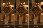 Three wooden tap fixtures shown side by side on a countertop, each with a different metal spout color labeled Silver, Gold, and Copper. Each fixture has a diamond-shaped wood panel with an engraved letter and decorative crest, and a small clear glass tumbler in front.