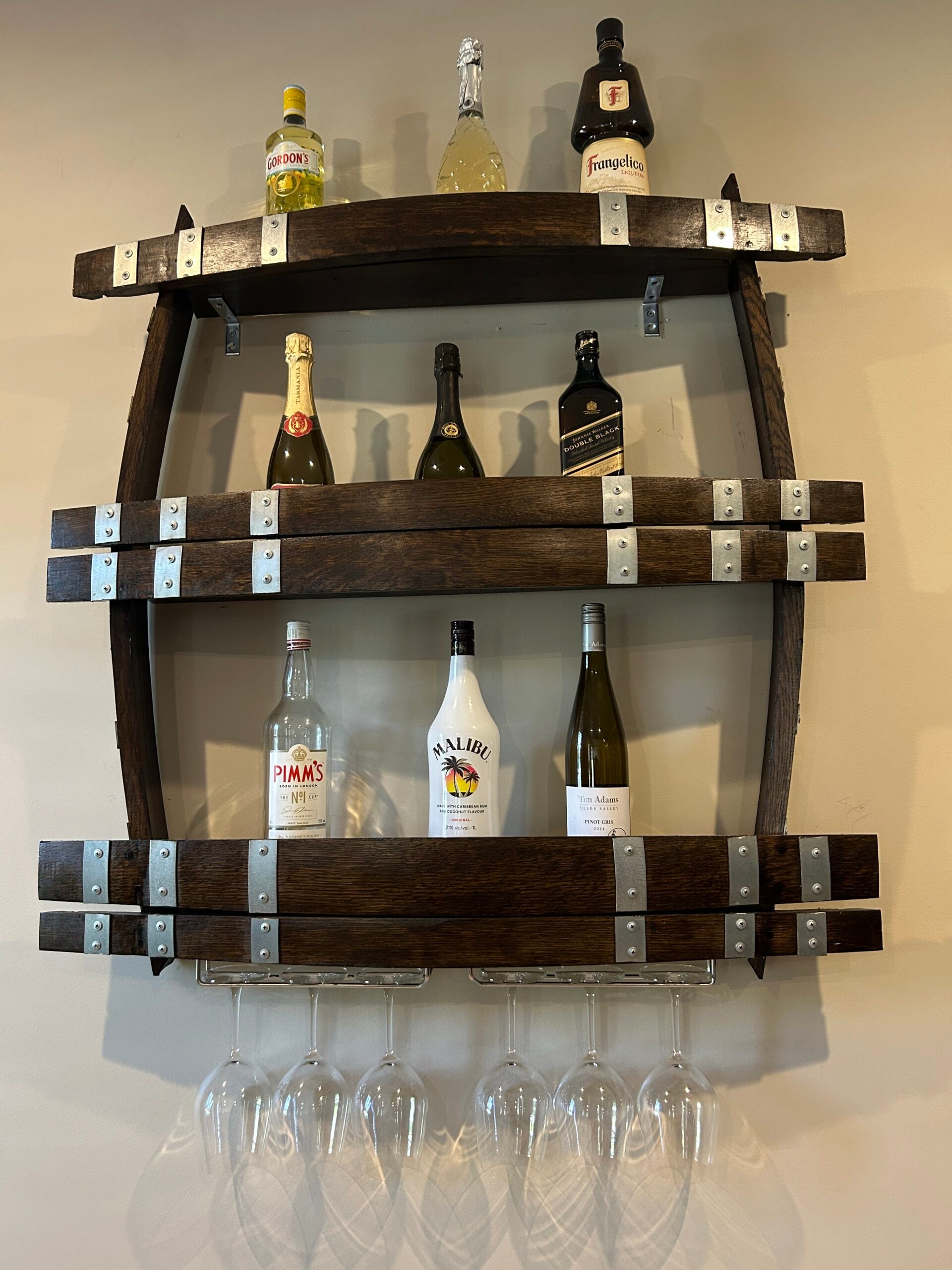 Wine barrel spirit rack handcrafted from reclaimed oak, featuring internal shelving and bottle storage – perfect for displaying whisky, wine, or barware
