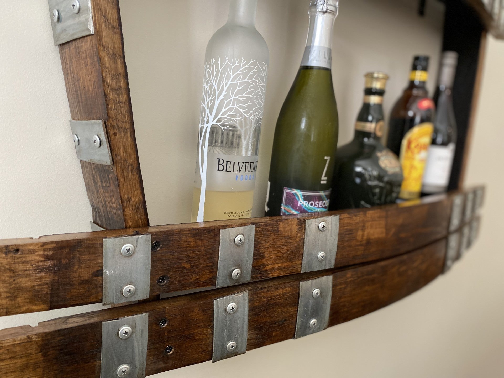 Wine barrel spirit rack handcrafted from reclaimed oak, featuring internal shelving and bottle storage – perfect for displaying whisky, wine, or barware