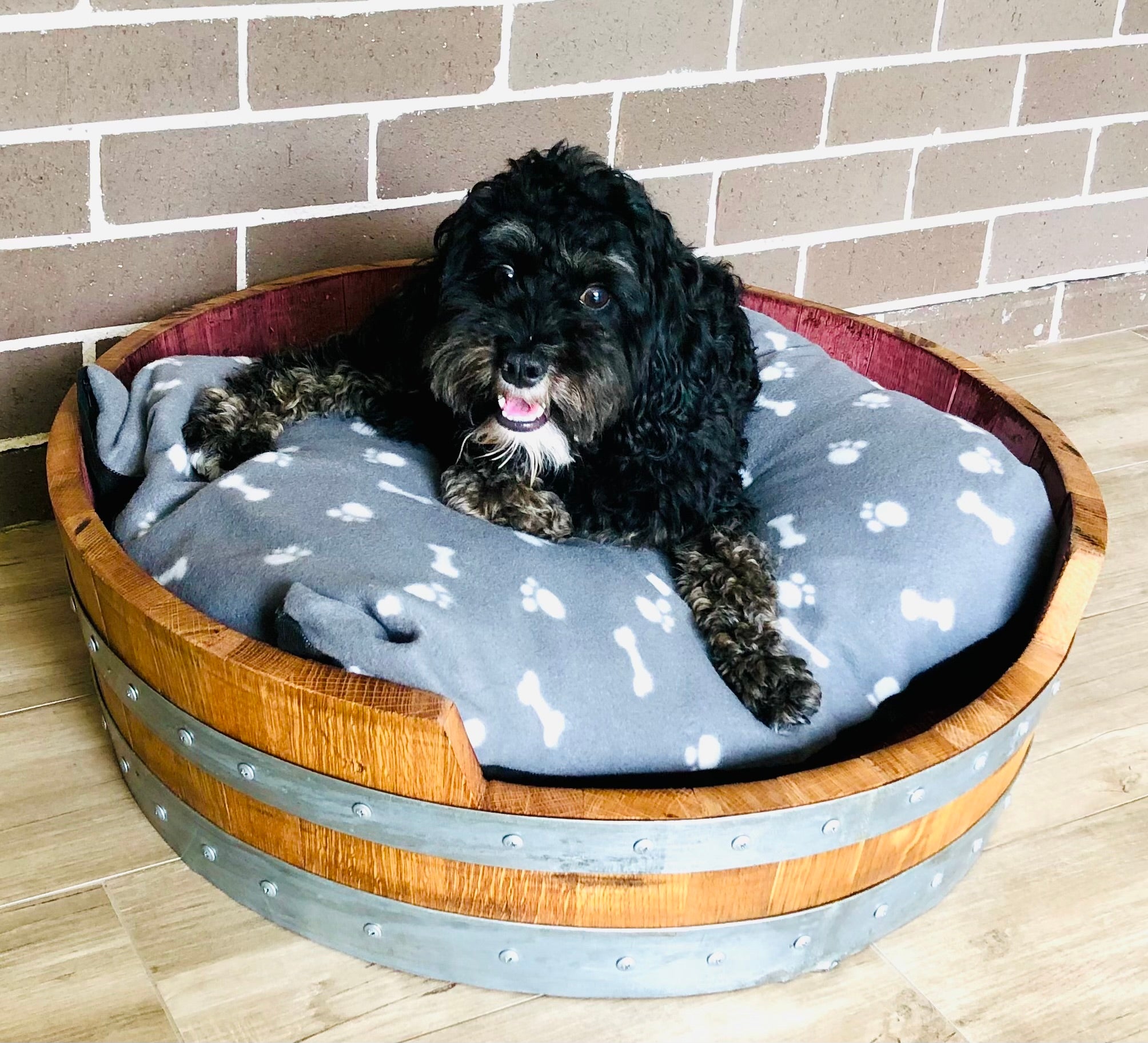 "Handcrafted wine barrel dog bed made from recycled oak barrels, featuring a curved design – eco-friendly pet furniture with rustic charm"