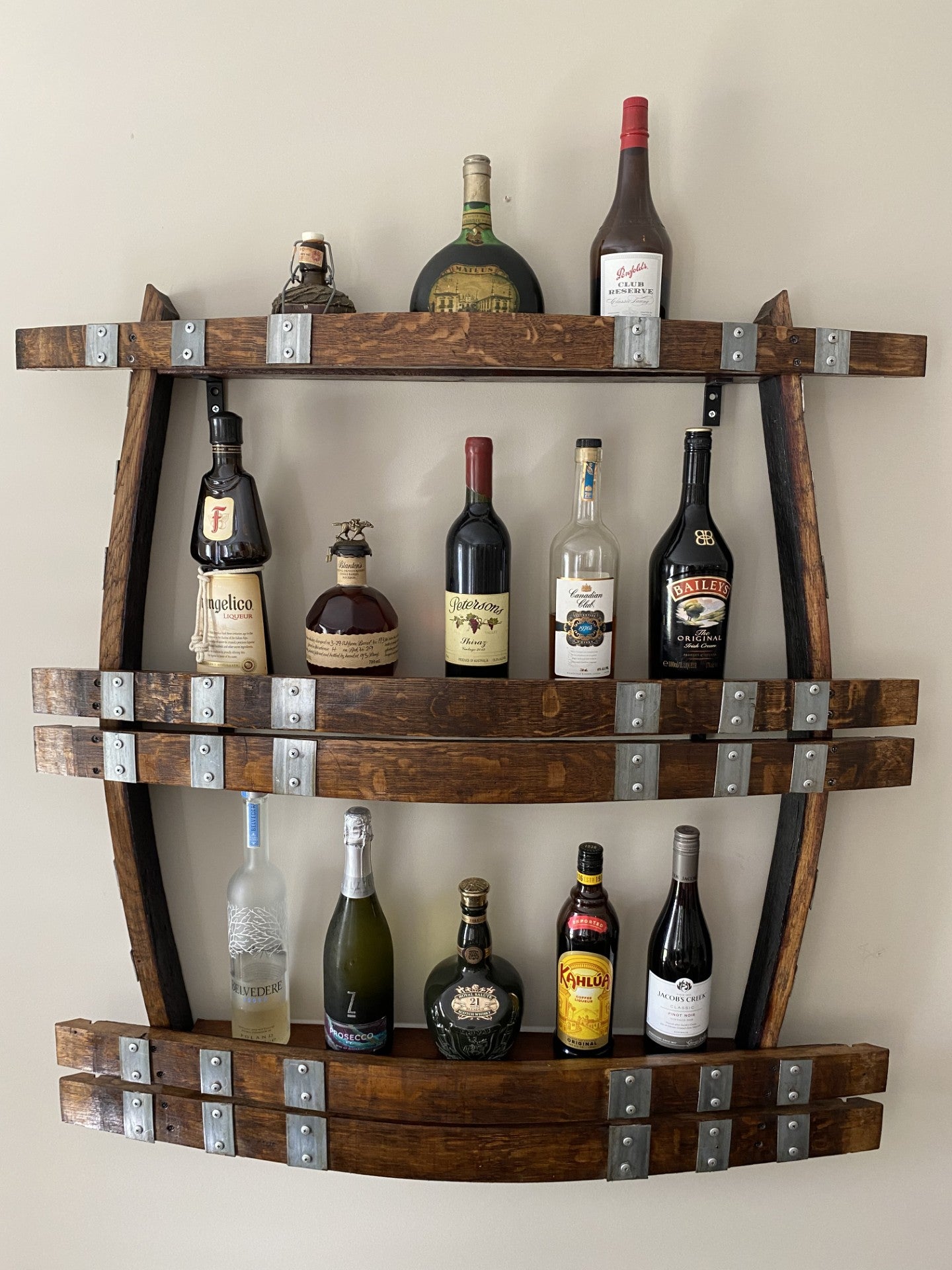 Wine barrel spirit rack handcrafted from reclaimed oak, featuring internal shelving and bottle storage – perfect for displaying whisky, wine, or barware