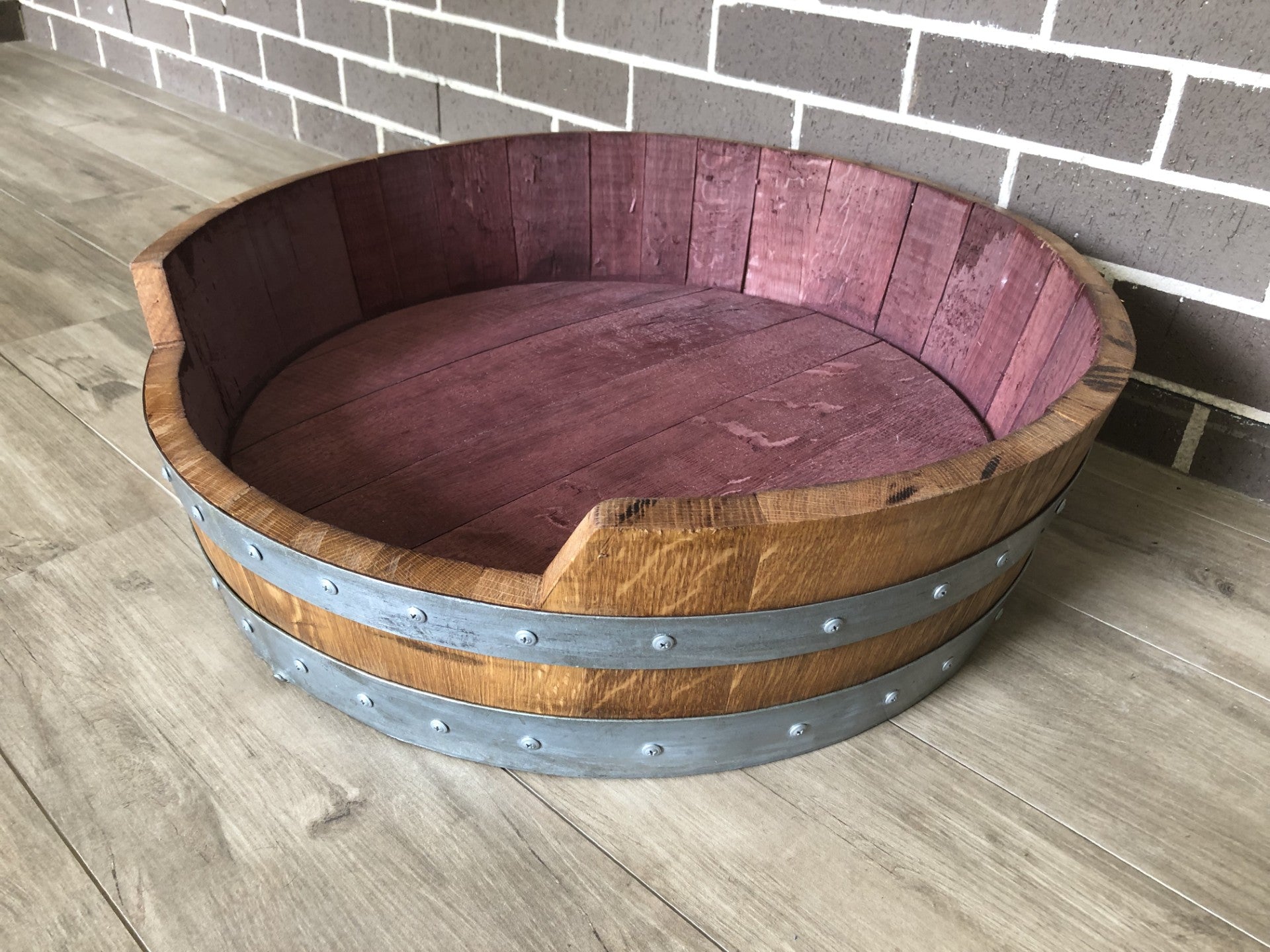 "Handcrafted wine barrel dog bed made from recycled oak barrels, featuring a curved design – eco-friendly pet furniture with rustic charm"
