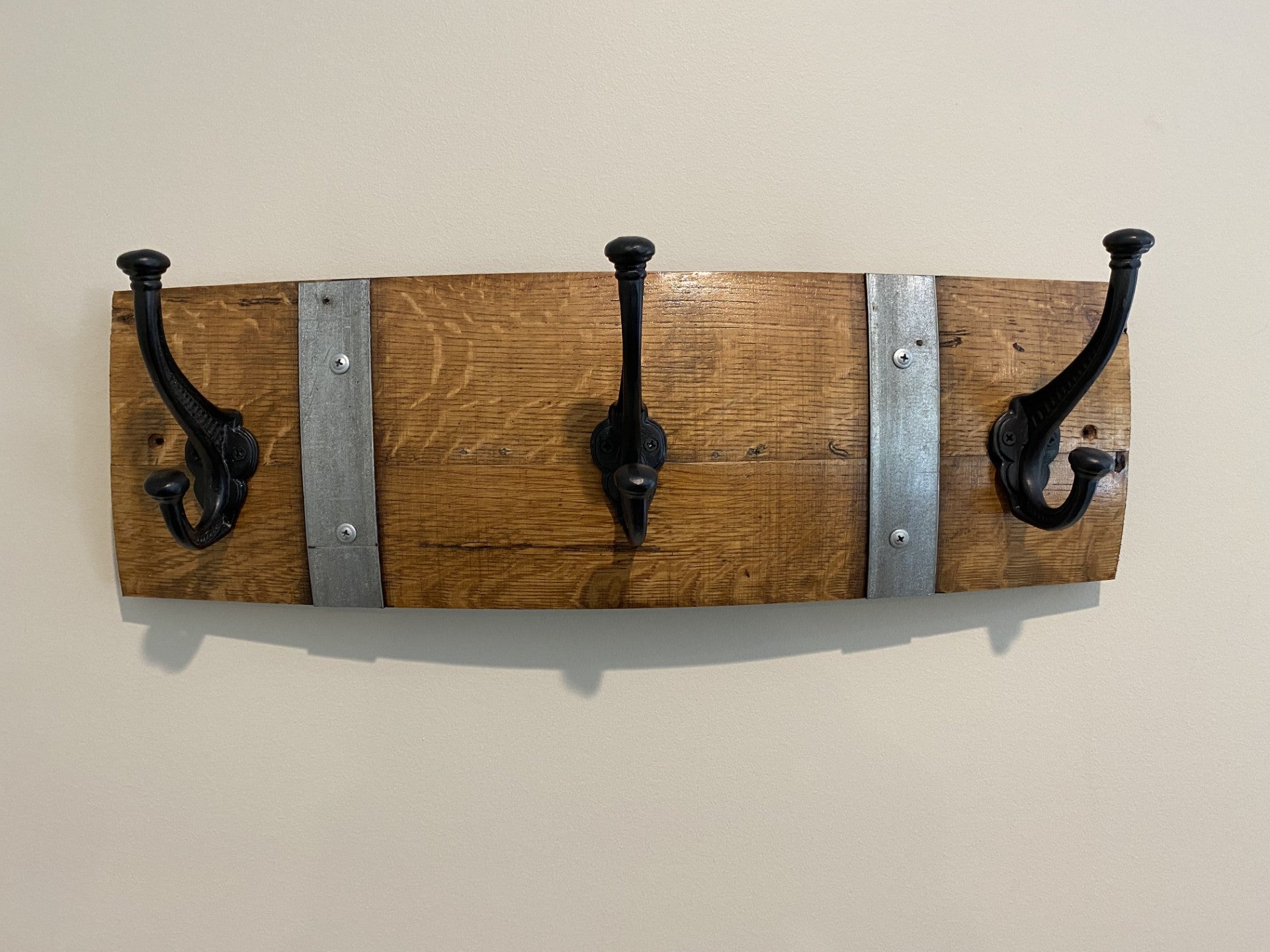 Rustic wine barrel coat rack handcrafted from reclaimed oak barrels with metal hooks – sustainable and stylish wall-mounted entryway organise