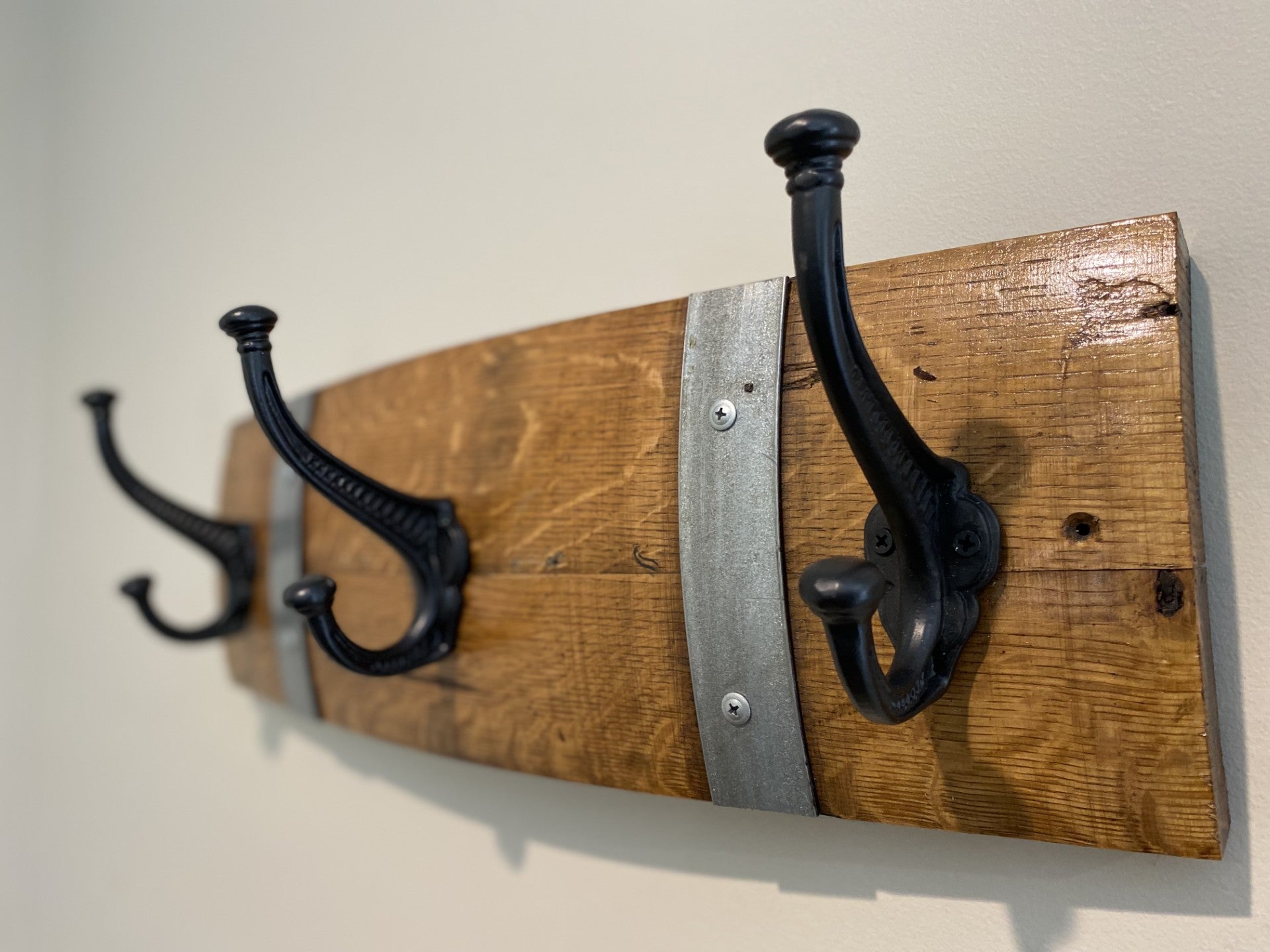 Rustic wine barrel coat rack handcrafted from reclaimed oak barrels with metal hooks – sustainable and stylish wall-mounted entryway organise