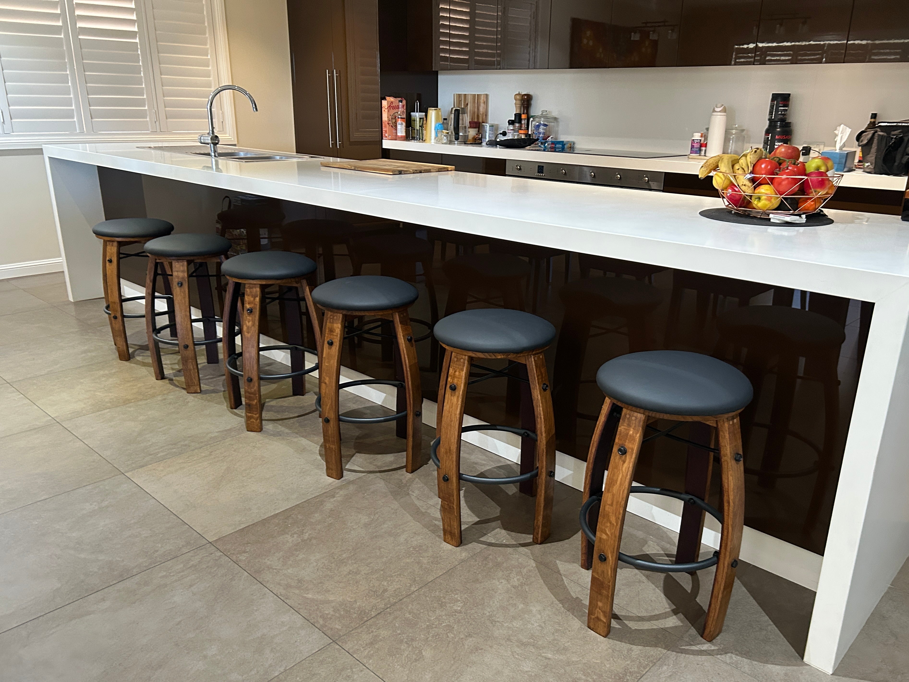 Wine barrel bar stools in modern Australian kitchen with black cushioned seats